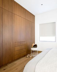 a white bed sitting next to a wooden wall