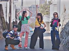 four young people standing on the side of a road with their arms in the air