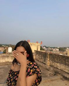 a woman covering her face while standing on top of a building