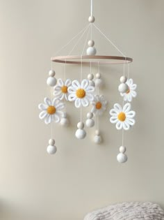 a crocheted mobile with white and yellow flowers hanging from it