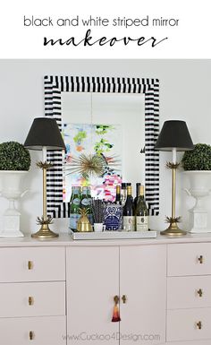 a white dresser with black and white striped mirror above it, next to two lamps