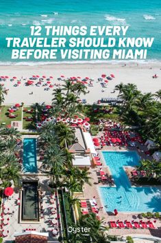 an aerial view of the beach with palm trees and red umbrellas