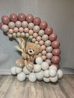 a teddy bear surrounded by balloons in the shape of an i love you balloon arch