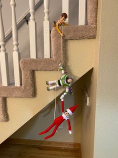 two elf dolls hanging from the side of a staircase