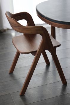 a wooden chair sitting next to a black table on top of a hard wood floor