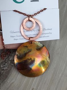 This boho style necklace features a pendant designed from a 1 5/8" copper blank that is fire painted using a propane torch to bring out the different colors in the metal. NOTE:  Different lighting will bring out the color more than other types of lighting. It is finished with two copper hoops in varying size. It comes with an 18" copper chain. It will ship in a gift box via USPS with tracking info provided. Artsy Gold Copper Jewelry, Artisan Copper Necklaces Nickel Free, Bronze Copper Necklace With Large Pendant, Artsy Brown Copper Jewelry, Handmade Rust Copper Necklaces, Artsy Hand Forged Copper Jewelry, Hand Forged Copper Round Pendant Necklace, Soldered Copper Rose Gold Necklace, Rose Gold Soldered Copper Necklaces