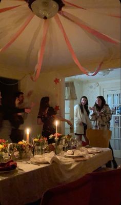 a group of people standing around a table with food and candles in front of them