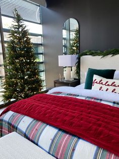 a bedroom decorated for christmas with red, white and green bedding in front of a large window