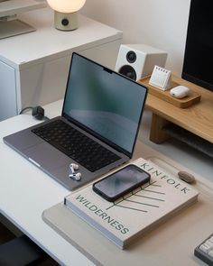 an open laptop computer sitting on top of a desk next to a phone and headphones