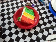 a slice of rainbow cake on a red plate