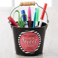 a bucket filled with pens and scissors on top of a table