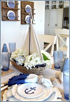 a sailboat centerpiece on a table with blue and white decor in the background