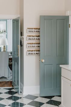 an open door leading to a dining room with white walls and black and white checkered floor