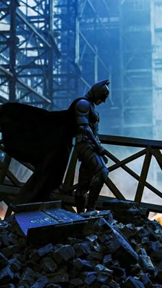 the dark knight is standing on top of a pile of rubble in batman's costume