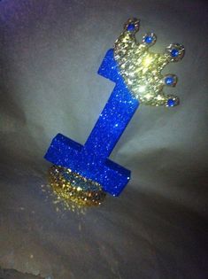 a blue and gold glittered number one with a crown on top