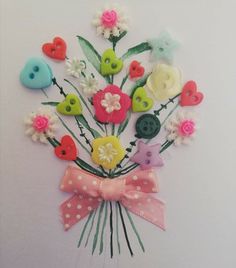 a bouquet of flowers with buttons attached to the stems is displayed on a white wall