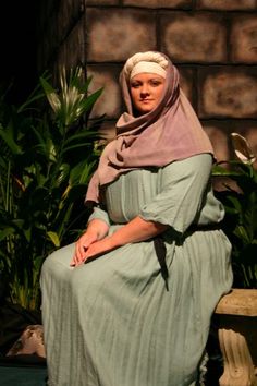 a woman sitting on top of a wooden bench