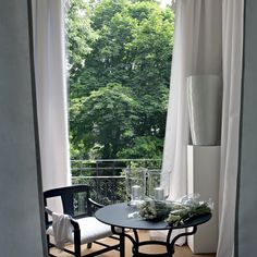 an open door leading to a balcony with two chairs and a table