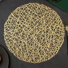 a placemat made out of gold wire on a table with silverware and utensils