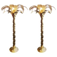 two tall brass palm trees with lights on them