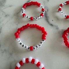 four red and white beaded bracelets sitting on top of a marble countertop