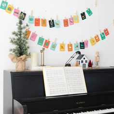 an open book sitting on top of a piano next to a christmas tree and garland