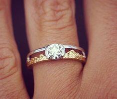 a close up of a person's hand with a diamond ring on their finger