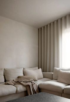 a living room filled with furniture and a large window covered in draping curtains