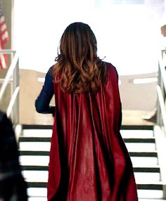 a woman in a red cape is walking down the stairs