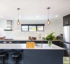 a modern kitchen with black and white cabinets, stainless steel appliances and bar stools