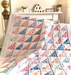 a bed with a quilt on top of it next to a white shelf and clock