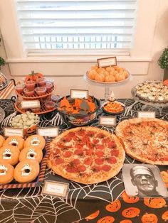 a table topped with pizzas covered in toppings next to other foods and desserts