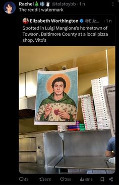 a man standing in front of a painting on top of a metal counter next to a pizza oven