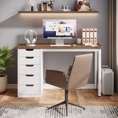 an office desk with a computer, books and plant on it in front of a gray wall