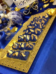 a blue and gold dessert table is set up with candy, candies, and other decorations