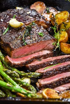 steak, potatoes and asparagus in a skillet with seasoning on top