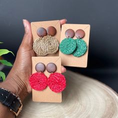 three pairs of handmade earrings are shown in front of a potted plant and brown paper