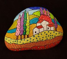 a painted rock with houses and trees in the background on a black surface that looks like it has been painted