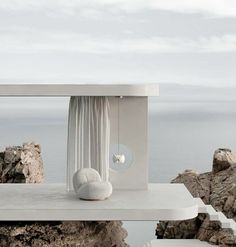 a white table sitting on top of a cliff next to the ocean