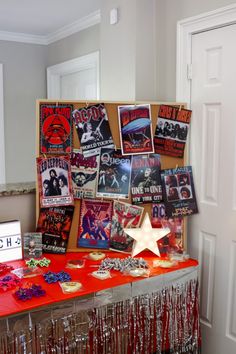 a red table topped with lots of records and pictures next to a white door covered in confetti