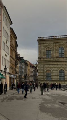 many people are walking around in an old european town square with tall buildings and cobblestone streets