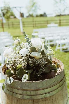 a wooden barrel filled with white flowers and greenery