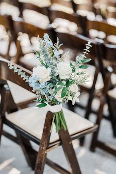 a bouquet of flowers sitting on top of a wooden chair in front of rows of chairs