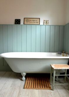 a white bath tub sitting next to a wooden stool