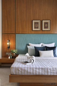 a bed with blue and white comforter in a bedroom next to two framed pictures on the wall