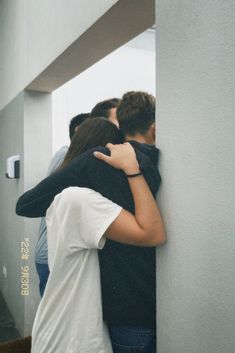 two people hugging each other while standing in front of a mirror with their backs to the wall