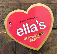 a valentine's day party sign hanging on a wooden wall with string attached to it