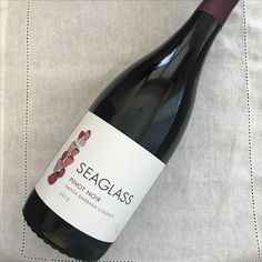 a bottle of seaglass pinot noir sits on a tablecloth with a white and red design