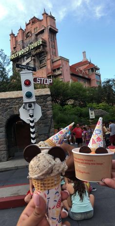 someone holding up an ice cream cone in front of the hollywood tower