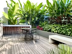 a wooden deck with plants and chairs on it